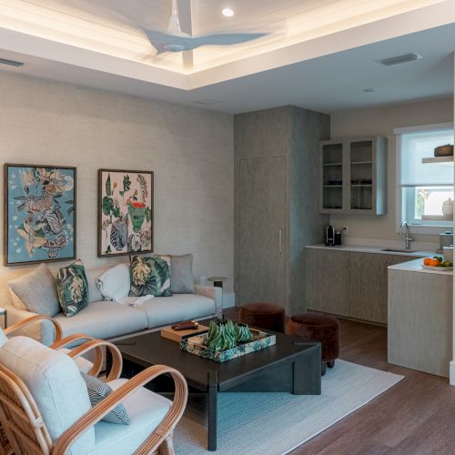 Cozy living room with a light blue sofa, wall art, and a small kitchen area in the background; warm vibes and soft decor.