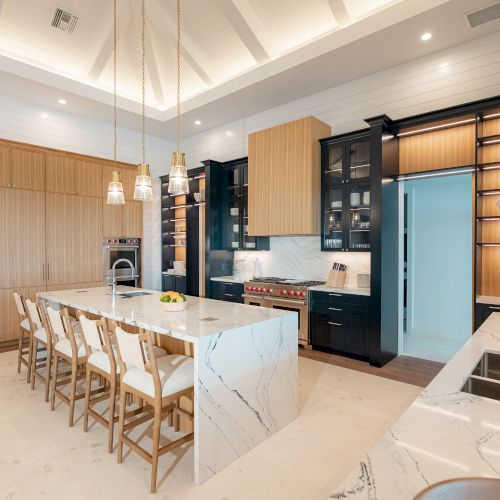 A modern, open-concept kitchen and living area with warm wood accents, a central island, floating shelves, and a sleek media wall, cozy lighting.