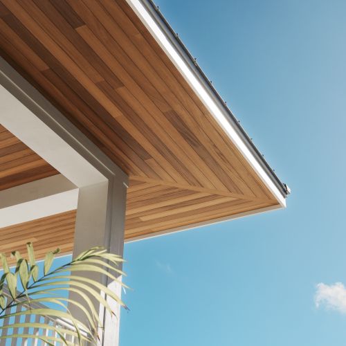 A wooden porch overhang with a clear blue sky and sunlight.