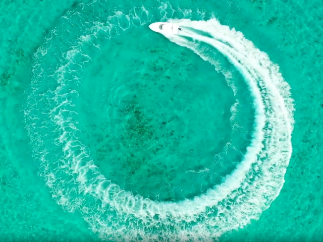 A turquoise background with a white circular brushstroke or spiral, resembling an abstract logo or design, minimal and modern.