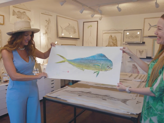 A nurse and patient in a hospital room look at an x-ray on a stand, discussing the image with a desk and chart nearby.